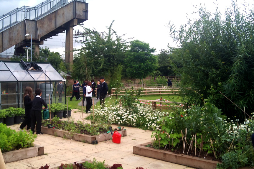 Northbury school with pupils at break time and kitchen garden and ugly footbridge over adjacent railway line